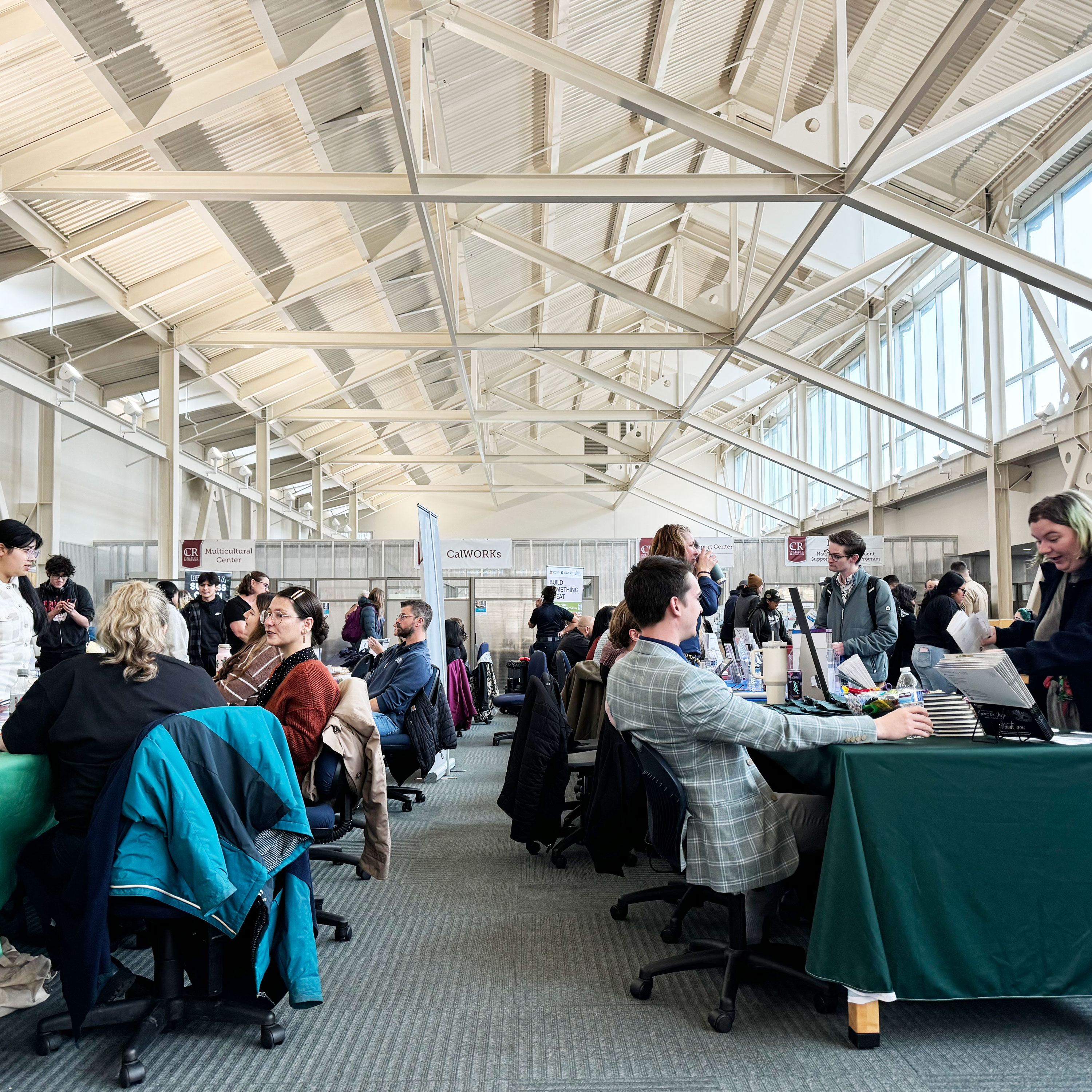 employers behind tables with merch and info, students milling around talking to employers